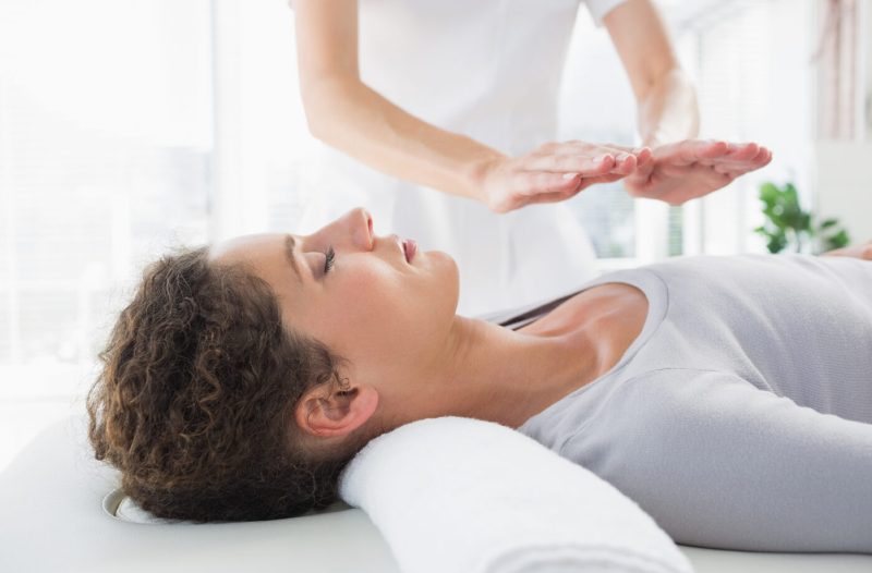 Attractive young woman having reiki treatment in health spa